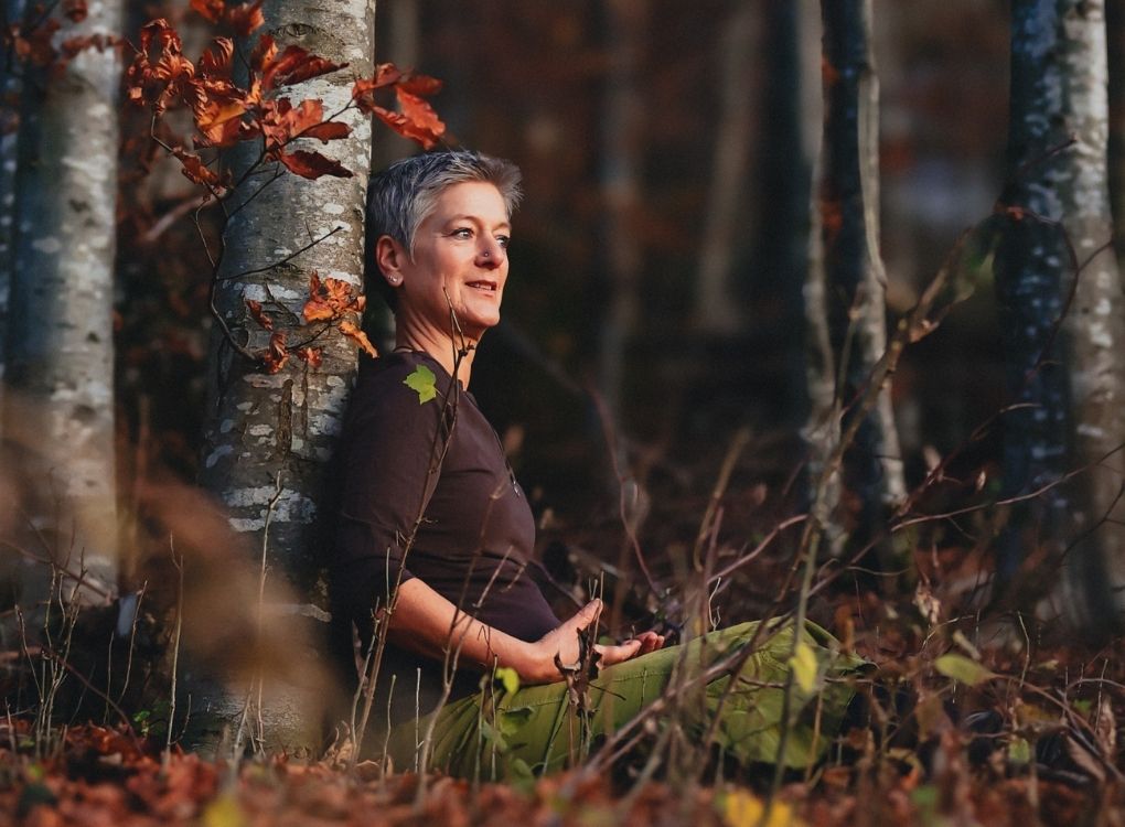 Vera sitzt im Wald unter einem Baum, verbunden mit den Elementarwesen oder auch Ashtara genannt.