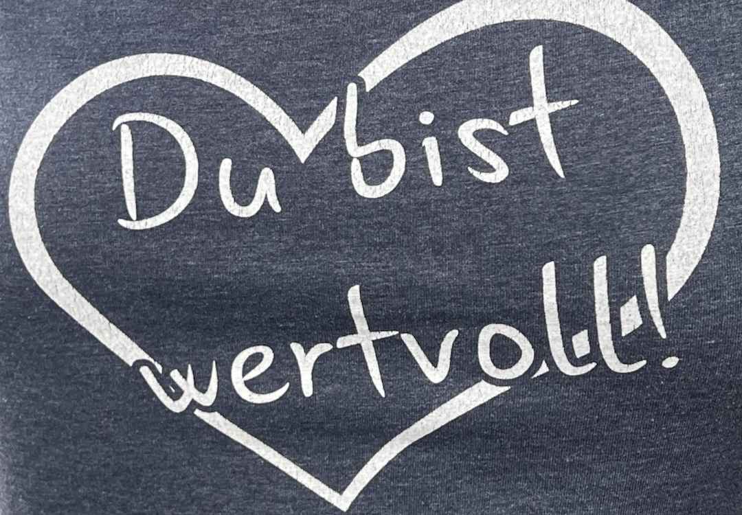 Du bist wertvoll umrahmt mit einem weißen Herz auf grauem Hintergrund.