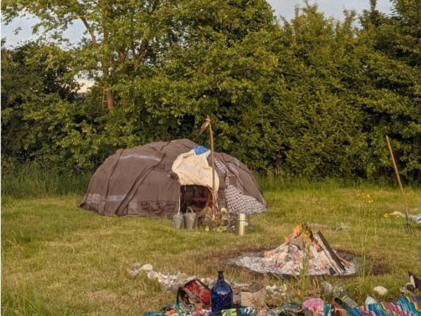 Schwitzhütte mit Altar und Steinerhitzung im Feuer